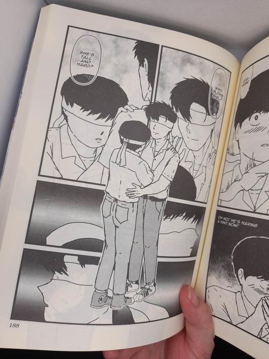 Photo of an open printed copy of Somewhere In My Past vol. 1, showing an interior page where two boys embrace at a bus stop.